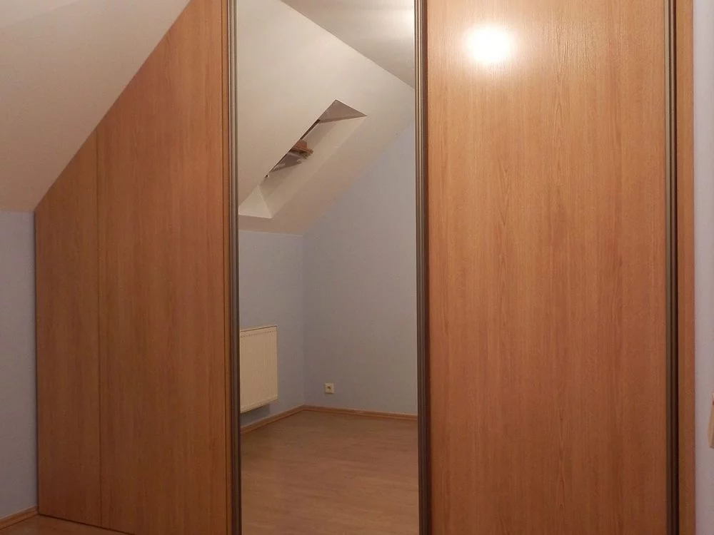 Zabudowa skośnego poddasza - szafa z drzwiami przesuwnymi z lustrem oraz szafka z frontem rozwieranym