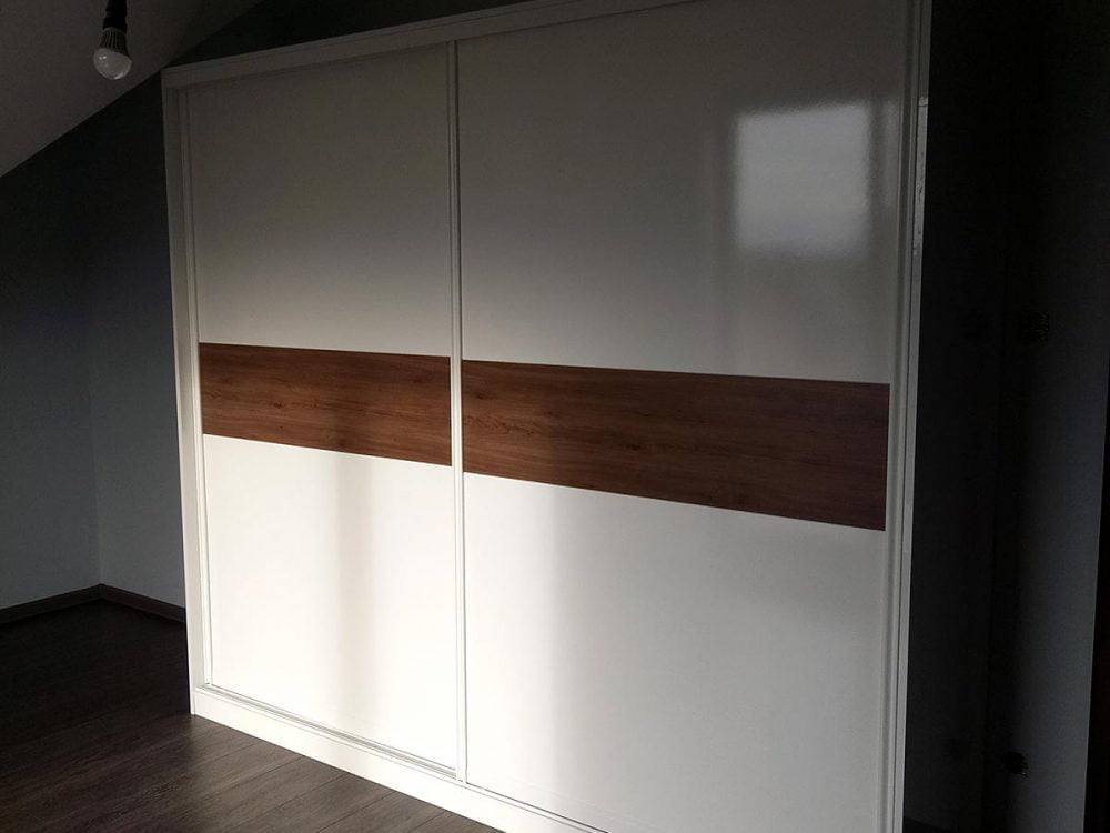 Biała szafa z systemem szerokich drzwi przesuwnych, z elementami w kolorze drewna